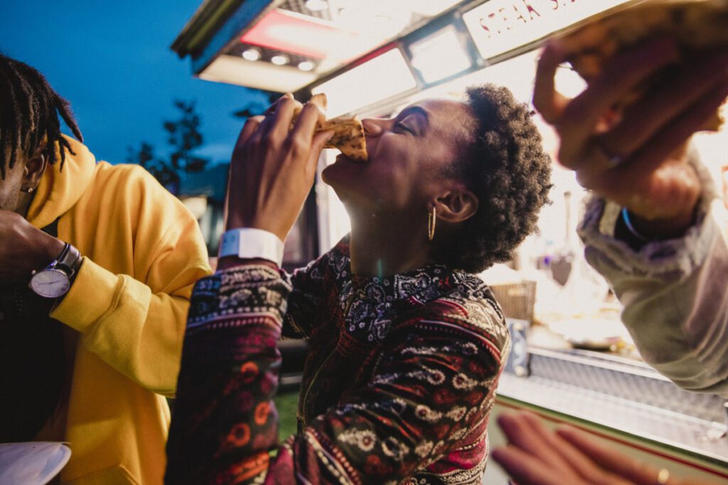 young woman eating pizza at festival